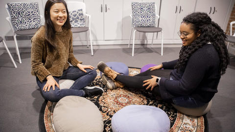 Two students sitting on floor mats of the serenity room in Grays basement.