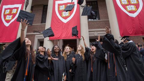 College students on Widener steps on Commencement Day throwing up their caps.
